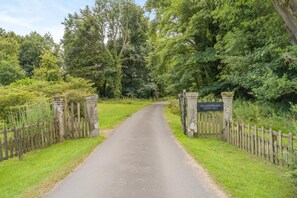 Eine Landstraße mit einem hölzernen Tor und einem Wegweiser.