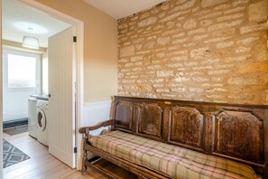 A room with a stone wall, a bench with a plaid cushion, and a washing machine. - 4 Bed in Ebberston (oc-h45939) (Ebberston)
