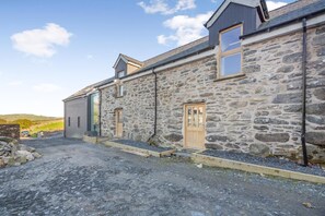 A stone building with a gravel driveway and a wooden door. - 5 Bed in Cerrigydrudion (oc-c45945) (Cerrigydrudion)