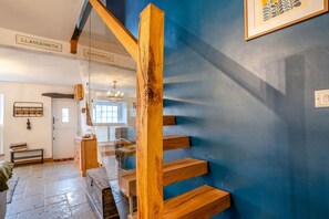 A staircase with wooden steps leading to a landing, a blue wall, and a door labeled 'LLANGENNITH'. - 2 Bed in Mumbles (oc-c45992) (The Mumbles)