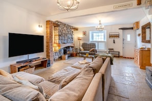 A cozy living room with a stone fireplace, a flat-screen TV, and a comfortable sofa. - 2 Bed in Mumbles (oc-c45992) (The Mumbles)
