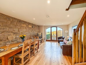 A spacious dining area with a stone wall, wooden furniture, and a view to a garden. - 2 Bed in North Curry (oc-c45884) (North Curry)