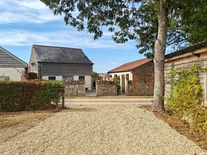 A gravel driveway leading to a stone building with a tiled roof, surrounded by greenery and a clear sky. - 2 Bed in North Curry (oc-c45884) (North Curry)