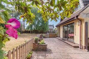 A patio with a wooden fence, potted plants, and a view of a house with a glass door. - 1 Bed in Wool (oc-c45498) (Wool)