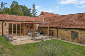 A brick house with a tiled roof, a patio with a table and chairs, and a garden with lavender. - 3 Bed in Sparham (oc-f46029) (Lyng)