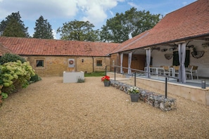 A courtyard with a brick building, a covered seating area, and a gravel path. - 3 Bed in Sparham (oc-f46029) (Lyng)