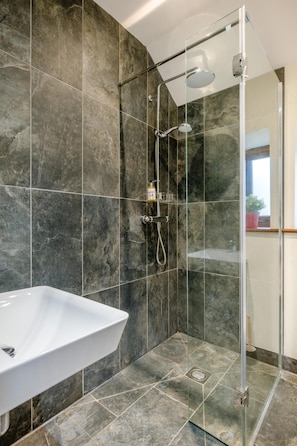A modern bathroom with a glass-enclosed shower, a white sink, and dark marble tiles. - 3 Bed in Sparham (oc-f46029) (Lyng)