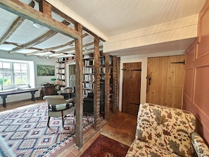 A room with exposed wooden beams, a bookshelf, a patterned sofa, and a patterned rug. - 3 Bed in Skilgate (oc-w46009) (Skilgate)