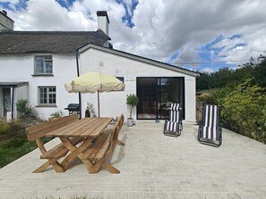 A patio with a wooden table and chairs, a yellow umbrella, and a sliding glass door leading to an interior space. - 3 Bed in Skilgate (oc-w46009) (Skilgate)