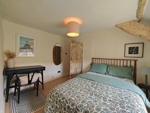 Ein Schlafzimmer mit einem Bett, einem Schreibtisch mit Stuhl, einem Spiegel und einer Lampe.