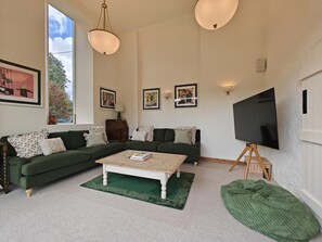 A living room with a green sofa, a coffee table, a television on a stand, and framed artwork on the walls. - 3 Bed in Skilgate (oc-w46009) (Skilgate)