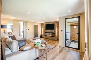 A modern living room with a sofa, a coffee table, a fireplace, and a television mounted on a stone wall. - 2 Bed in Greenhow Hill (oc-h46025) (Greenhow Hill)