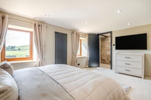 A bedroom with a large bed, a dresser, a television, and a stone wall. - 2 Bed in Greenhow Hill (oc-h46025) (Greenhow Hill)