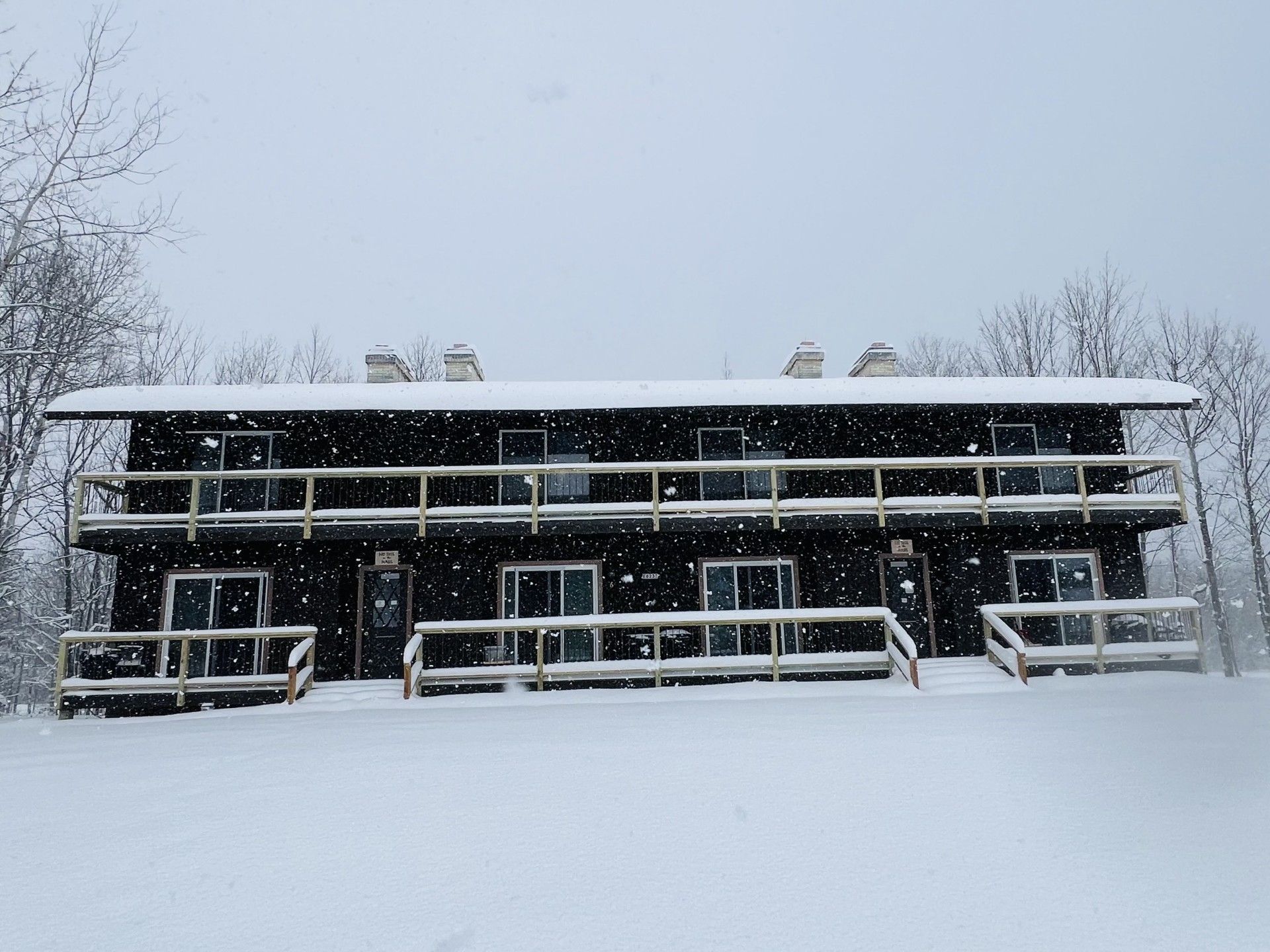 A two-story building with a flat roof and multiple windows, surrounded by snow.