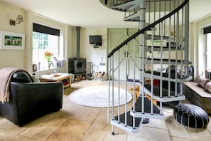 Ein modernes Wohnzimmer mit einer Wendeltreppe, einem Kamin und einer gemütlichen Sitzecke.