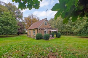 Ein zweistöckiges Haus mit Ziegelaußenwand, einem Ziegeldach und einem umzäunten Garten.