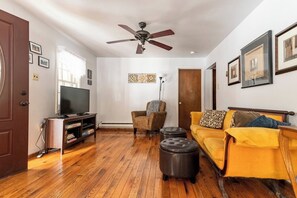 A living room with a television, a ceiling fan, a sofa, and a chair. - Wonderful 3-bedroom house with AC in charming Lake Harmony (Lake Harmony)