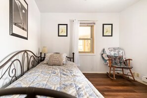 A bedroom with a bed, a chair, a window, and two framed pictures on the wall. - Wonderful 3-bedroom house with AC in charming Lake Harmony (Lake Harmony)