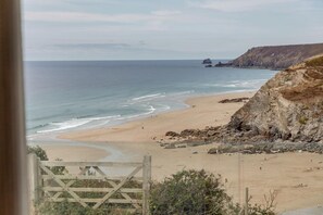 A coastal beach with a rocky cliff, a sandy shore, and a view of the sea. - 4 Bed in Porthtowan (oc-m45962) (Porthtowan)