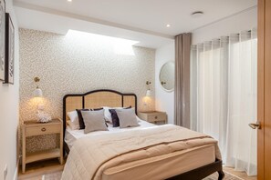 A bedroom with a bed, bedside tables, a mirror, and a window with curtains. - 4 Bed in Porthtowan (oc-45963) (Porthtowan)