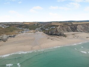A coastal landscape with a sandy beach, cliffs, and a small settlement. - 4 Bed in Porthtowan (oc-45963) (Porthtowan)