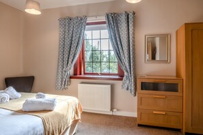 A bedroom with a bed, a window with curtains, a radiator, and a wooden cabinet. - 2 Bed in Berwick-upon-Tweed (oc-s46040) (Kyloe)