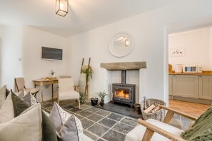 A cozy living room with a stone fireplace, a dining area with a table and chairs, and a kitchen with cabinets and appliances. - 1 Bed in Trevelmond (oc-46051) (Trevelmond)