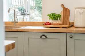 A kitchen with a wooden countertop, a cutting board, a potted plant, a loaf of bread, and a coffee maker. - 1 Bed in Trevelmond (oc-46051) (Trevelmond)