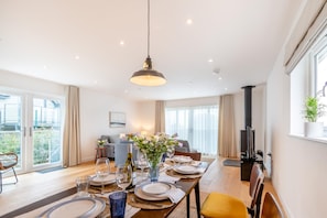 A dining area with a table set for four, a sofa, and a television in a modern apartment. - 3 Bed in Broad Haven (oc-r45937) (Broad Haven)