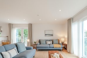 A modern living room with a sofa, a coffee table, and a painting on the wall. - 3 Bed in Broad Haven (oc-r45937) (Broad Haven)