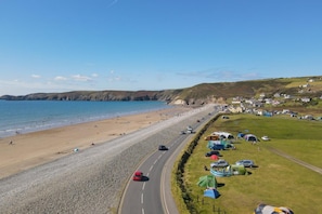 A coastal road with beach access, vehicles, and tents on the roadside. - 3 Bed in Broad Haven (oc-r45937) (Broad Haven)