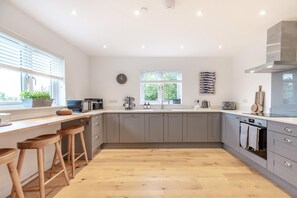 A modern kitchen with grey cabinets, a wooden countertop, and a large window providing natural light. - 3 Bed in Broad Haven (oc-r45937) (Broad Haven)
