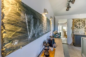 Ein Flur mit einer Willkommensschild, einer Kaffeemaschine und einer Uhr an der Wand.