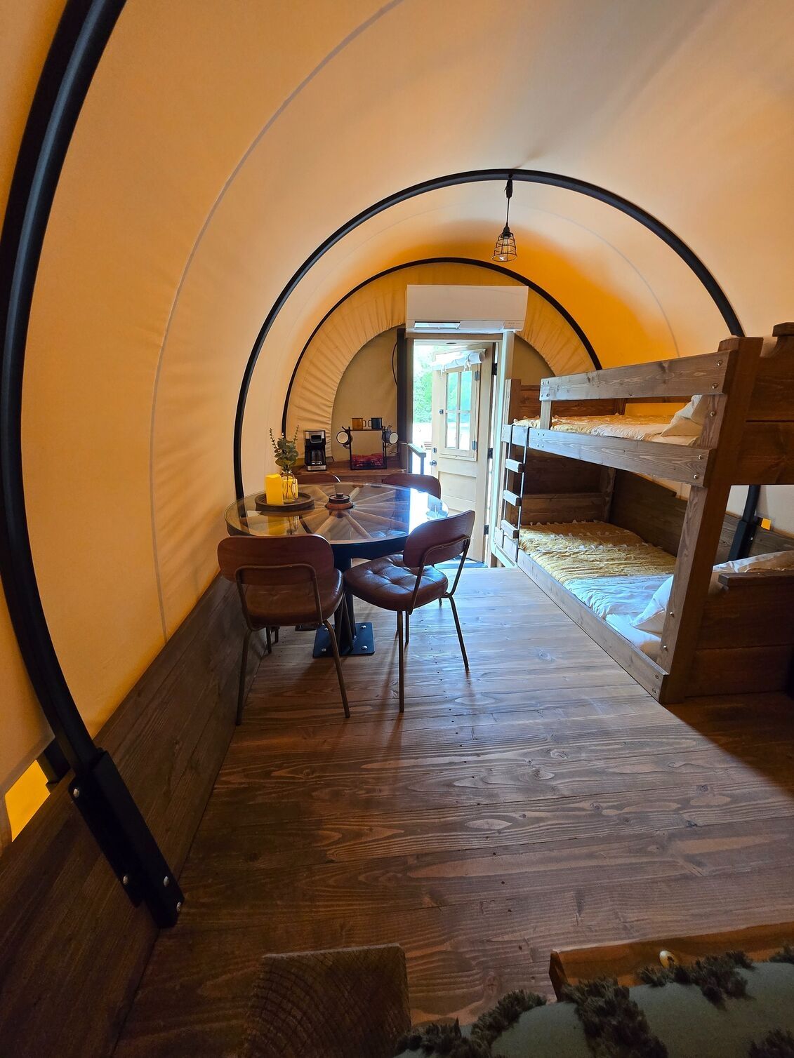 A cozy interior with a wooden table, chairs, and a bunk bed.