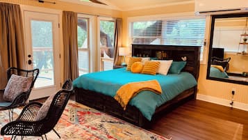 Un dormitorio con una cama grande, un ventilador de techo y vistas al exterior a través de las ventanas.