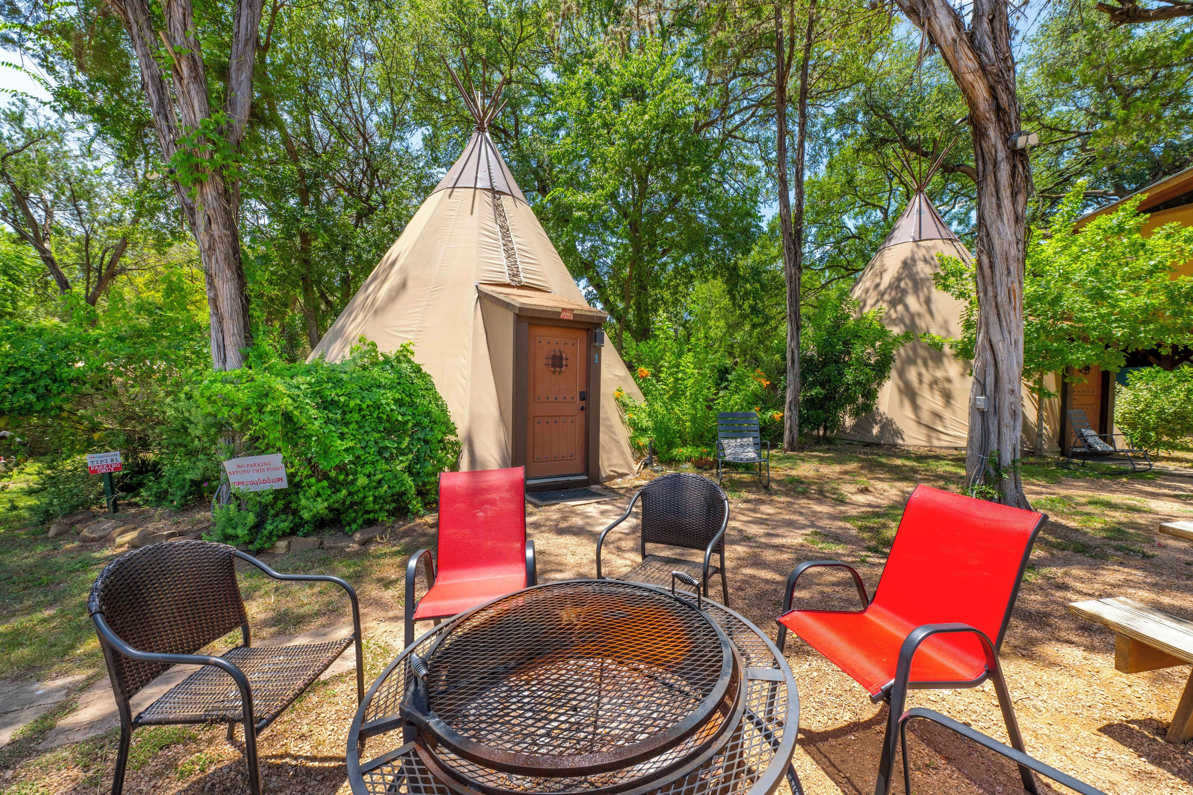 A campsite with a teepee, a fire pit, and seating.