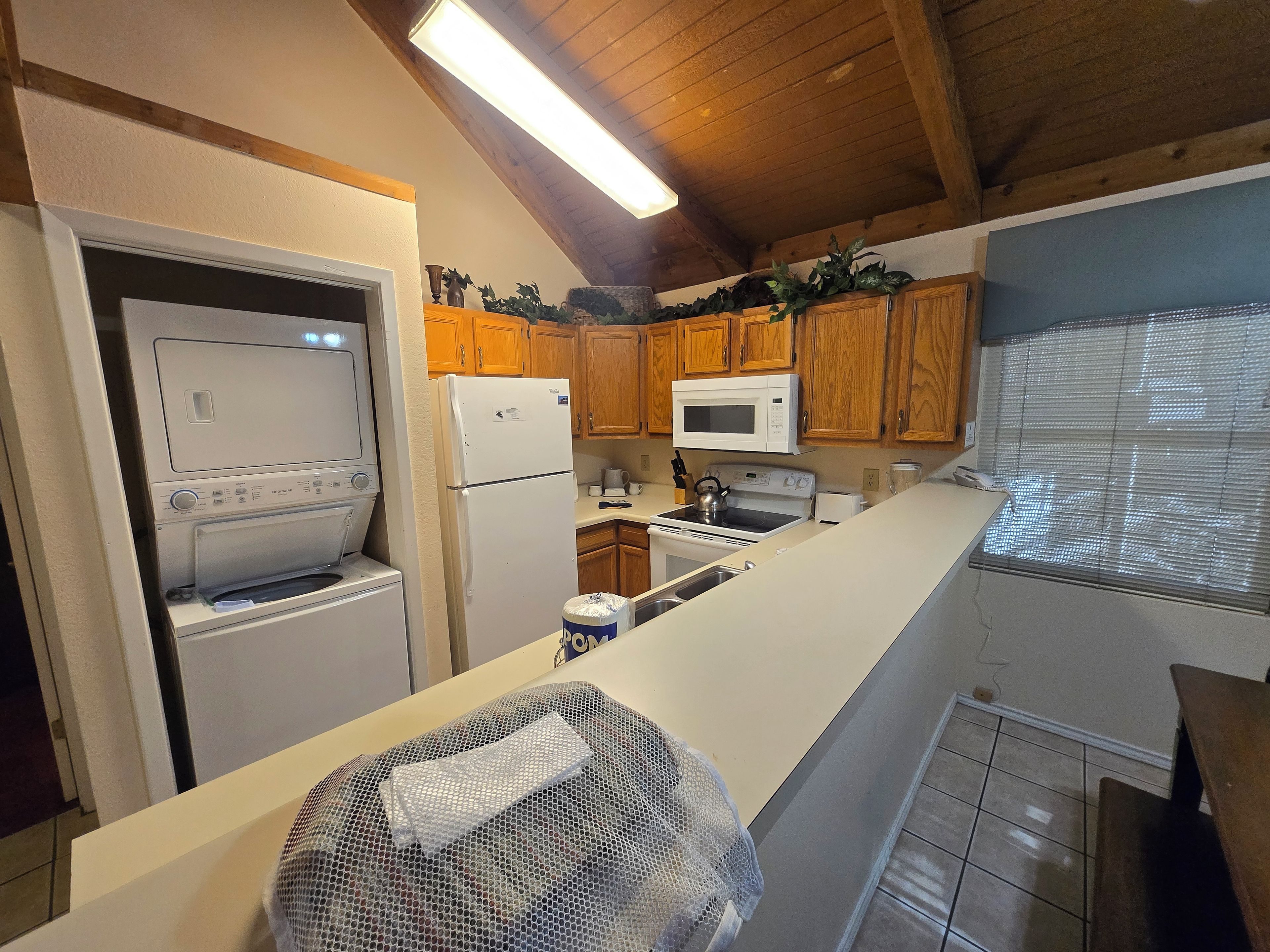 A compact kitchen with wooden cabinets, a microwave, a refrigerator, and a stove.