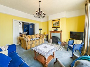 Ein Wohnzimmer mit einer Sofagarnitur, einem Couchtisch, einem Kamin und einem Fernseher.