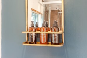 A mirror with a wooden shelf holding three bottles of MB products. - 1 Bed in Batheaston (oc-f45918) (Batheaston)