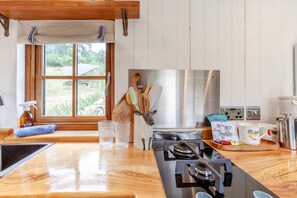 Een moderne keuken met een houten aanrecht, roestvrijstalen apparatuur en een raam met uitzicht op groen.