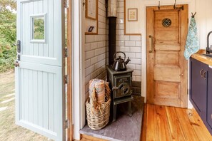 A rustic kitchen with a wood stove, a basket of yarn, and a wooden door. - 1 Bed in Batheaston (oc-f45918) (Batheaston)