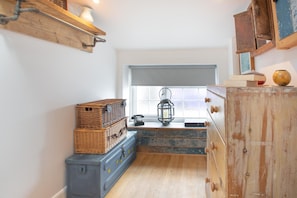 A compact kitchen with wooden cabinets, a window with a view, and a vintage-style lantern. - 1 Bed in Abersoch (oc-l46031) (Abersoch)