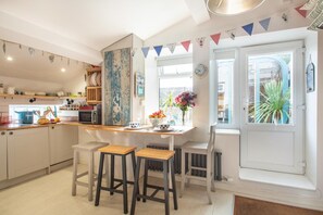 Een keuken met een eethoek, een raam met uitzicht en een klok aan de muur.