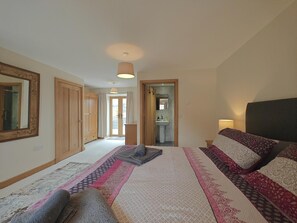 A bedroom with a large bed, a wardrobe, a mirror, and a bathroom visible through an open door. - 3 Bed in Talybont (oc-b46034) (Llandre)