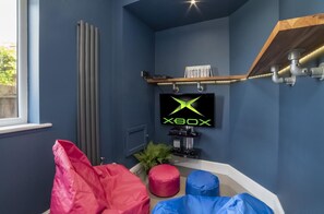 A room with a blue wall, a mounted television displaying the Xbox logo, a radiator, a shelf with books, and a gaming setup. - 7 Bed in Earswick (oc-s46053) (Earswick)