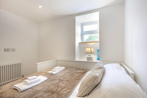 Ein Schlafzimmer mit Bett, Fenster, Lampe und Heizkörper.