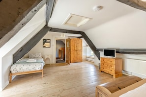 A bedroom with a sloped ceiling, a bed, a dresser, and a television. - 3 Bed in Bridport (oc-f45448) (Bothenhampton)