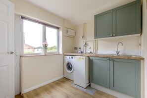 Eine kleine Küche mit Waschmaschine, Spüle und Fenster mit Blick.