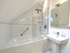 A modern bathroom with a glass-enclosed shower, a white bathtub, and a sink with toiletries. - 3 Bed in Thornham (oc-h45956) (Thornham)
