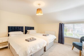 A bedroom with two beds, a bedside table, a chair, a window with curtains, and a hanging light fixture. - 2 Bed in Thrussington (oc-42472) (Thrussington)